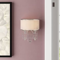 a wall mounted lamp next to a pink wall with a white flower on the side