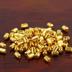 a pile of gold colored beads sitting on top of a wooden table