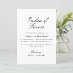 a white wedding card with the words in black ink on it and a vase full of flowers