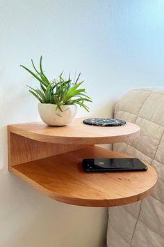 a wooden shelf holding a cell phone and a potted plant on top of it