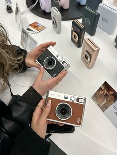 a woman holding an old camera in front of other cameras on display at a store