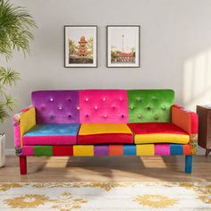 a multicolored couch sitting on top of a wooden floor next to a potted plant