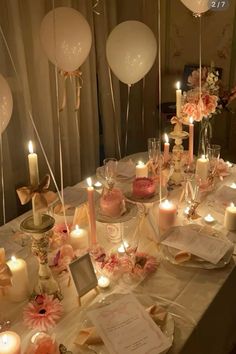 a table topped with lots of white balloons and candles