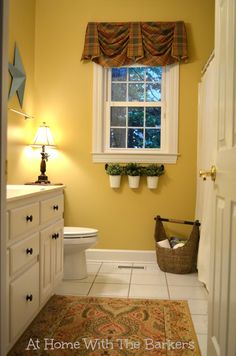 a white toilet sitting next to a window in a bathroom on top of a rug