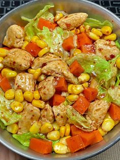 a bowl filled with chicken, carrots and lettuce next to a keyboard