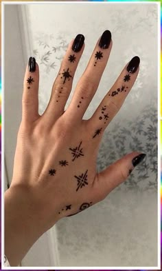 a woman's hand with black nail polish and stars on it