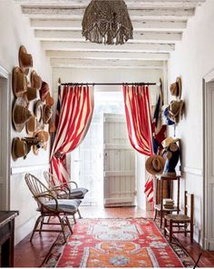 the hallway is decorated with many hats and rugs on the floor, along with two chairs