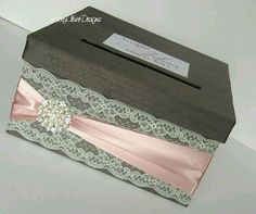 an open box with pink ribbon and lace on it