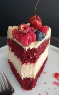 a slice of red velvet cake with white frosting and fresh berries on the top