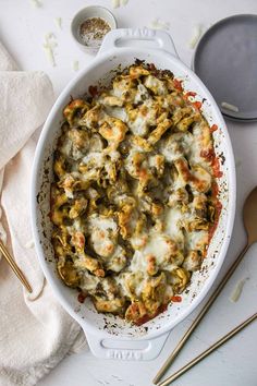 a casserole dish with cheese and spinach in it on a white surface