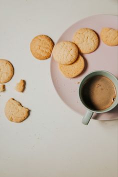 some cookies and a cup of coffee on a pink plate next to the cookie pieces