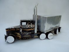 a toy truck made out of metal with wheels and an open box on the back