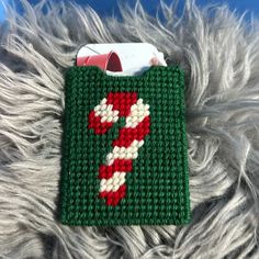 a crocheted green and white christmas bag with candy cane on it sitting on a furry surface