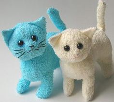 two small stuffed cats one is white and the other is light blue with black eyes