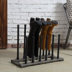 four pairs of boots are lined up on a rack in front of a brick wall