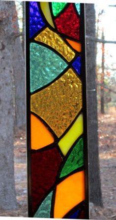 a colorful stained glass window sitting in the middle of a forest