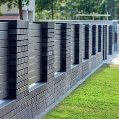 a row of windows on the side of a brick wall next to a grassy field