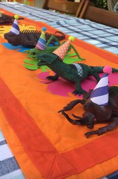 there are many toy animals that are on the table with party hats and decorations in front of them