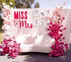 a white couch sitting next to a wall with pink flowers on it and a sign that says miss to mrs