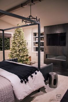 a bedroom with a christmas tree in the corner and a tv mounted on the wall