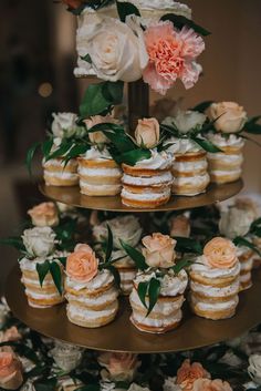 a three tiered cake with flowers on it and cupcakes in the middle