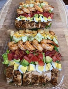 several trays filled with different types of food on top of a wooden cutting board