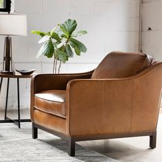 a brown leather chair sitting next to a table with a potted plant on it