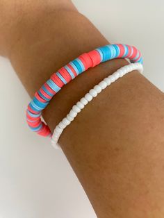 a woman's arm with two different colored bracelets on it, one is white and the other is blue