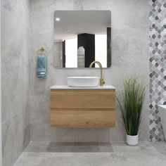 a bathroom with a sink, mirror and plant in the corner on the counter top