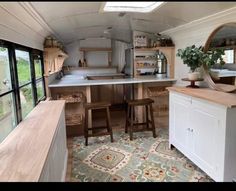 a kitchen area with stools next to a counter and sink in a trailer home