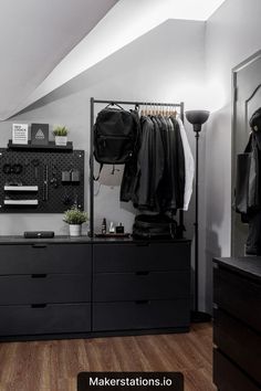 a bedroom with black dressers and clothes hanging on the rack in front of it