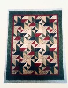 an old quilt hanging on the wall in front of a white wall with black and red accents