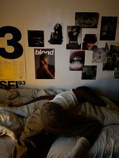 a person laying on a bed in front of a wall covered with pictures and posters