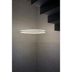 a circular light fixture hanging from the ceiling in a room with white walls and stairs