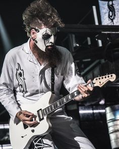 a man with white face paint playing an electric guitar