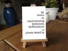 a wooden easel with a sign on it that says, my brain is experiencing technical differences please stand by