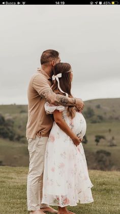 a man and woman standing next to each other on top of a lush green field