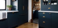 a kitchen with dark blue cabinets and white counter tops