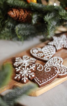 some cookies are on a cutting board next to a christmas tree and pine cones with snowflakes