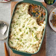 a casserole dish with mashed potatoes, meat and vegetables on the side