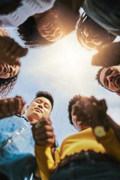 a group of people standing in a circle with their hands together and looking up at the sky