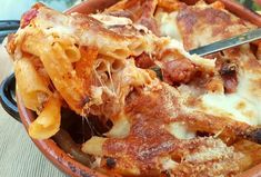 a close up of a plate of food with pasta and meat on it, next to a fork