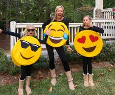 three women dressed in costumes holding up smiley faces