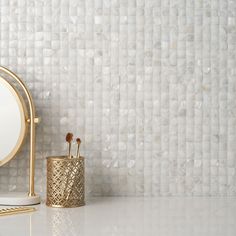 a white counter top with a mirror and brush holder on it next to a gold stand