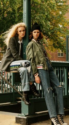 two people sitting on a bench in front of a street sign