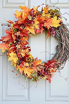 a wreath with autumn leaves hanging on the front door