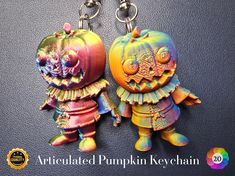 two colorful key chains are hanging on a black surface with an orange and yellow pumpkin