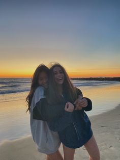 two girls hugging on the beach at sunset