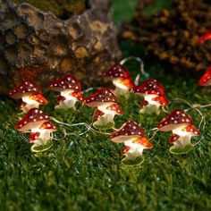 small red and white mushrooms are on the grass next to some rocks with lights in them