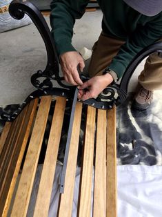 a person working on a bench made out of wooden slats and wrought iron bars